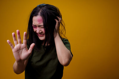 Beautiful young woman standing against yellow background