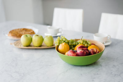 Fresh fruit, peaches, grapes and oranges in a plate on the marble table in the kitchen. healthy