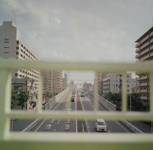 Vehicles on road in city against sky