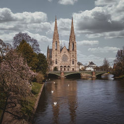 View of building by river against cloudy sky