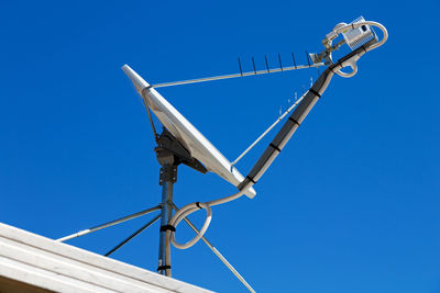 Low angle view of telephone pole against clear blue sky