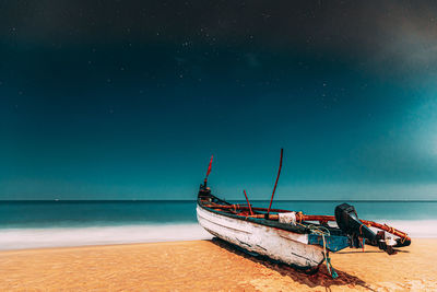 Boat moored on beach against sky
