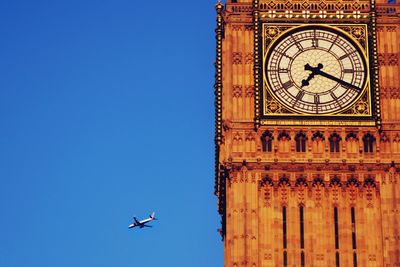 Low angle view of airplane flying against clear blue sky