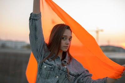 Portrait of woman standing against orange sky