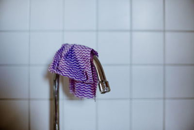 Close-up of washcloth hanging on water tap in front of kitchen tiles
