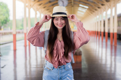 Portrait of smiling young woman wearing hat standing outdoors