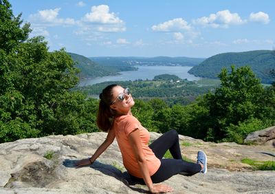 Young woman sitting on tree against sky