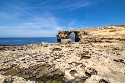 Scenic view of rock formation by sea against sky