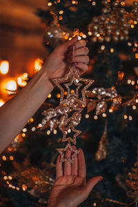 Female hand holding golden christmas stars against a background of festive golden bokeh lights