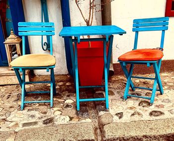 Empty chairs and table against building