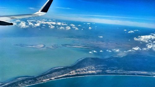 Aerial view of aircraft wing over sea against sky