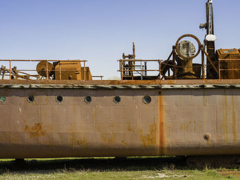 Rusty metallic structure on field against clear sky