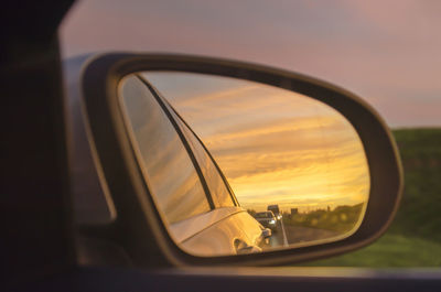 View in the rear view mirror on a road during a very colorful sunset