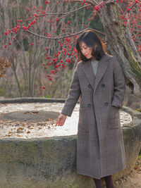 Woman standing by tree trunk during winter