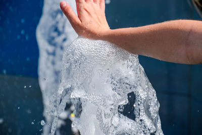 Cropped hand touching water in fountain