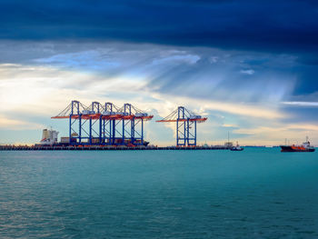 Cranes at commercial dock against sky