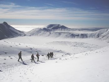 People on snowcapped mountain against sky