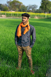 Teenage boy looking away while standing on field