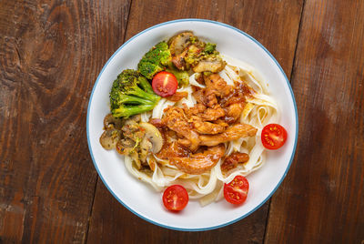 Udon with meat and vegetables in yakiniku sauce in a gray plate on a wooden table. horizontal photo