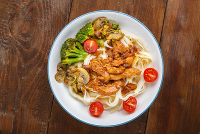 Udon with meat and vegetables in yakiniku sauce in a gray plate on a wooden table. horizontal photo