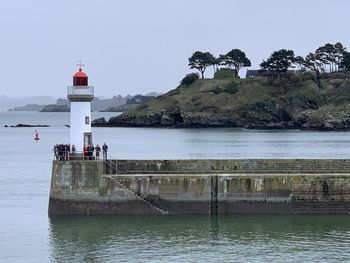 Lighthouse by sea against sky