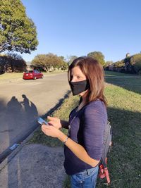 Woman standing by car on road against sky