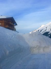 Snow covered houses by building against sky