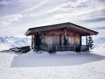 Wooden built structure on snow covered land against sky