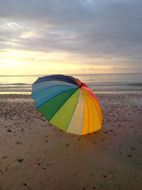 Umbrella at beach against sky during sunset
