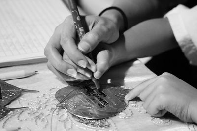 Cropped hands of people writing on metallic leaf at home