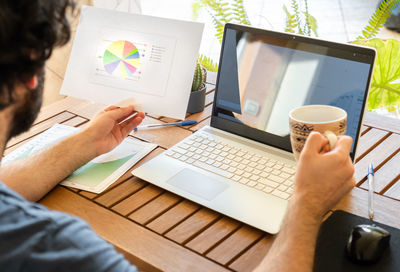 Midsection of man using laptop on table