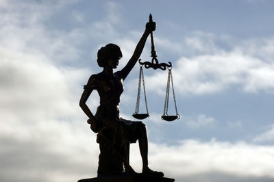 Low angle view of silhouette statue against sky