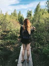 Rear view of woman standing against tree