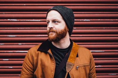 Portrait of man wearing hat standing against wall