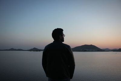 Man looking at sea against sky during sunset