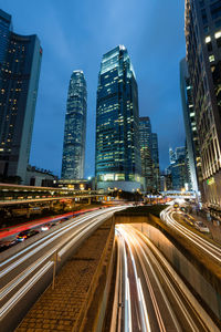 Light trails on road amidst buildings against sky in city