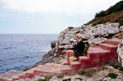 Woman sitting on steps at beach