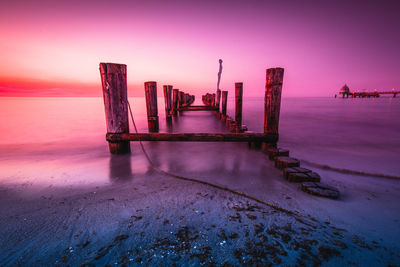 Pier over sea against sky during sunset