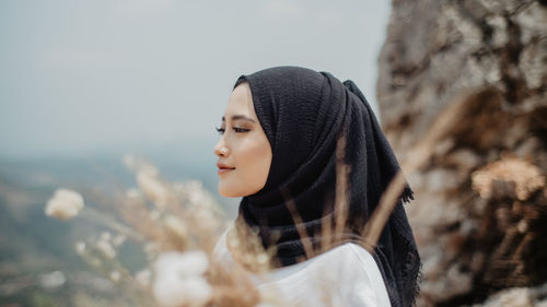 Young woman looking away while standing on snow