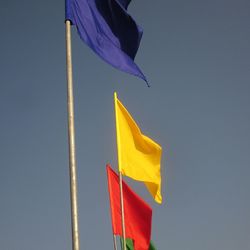 Low angle view of flags against blue sky