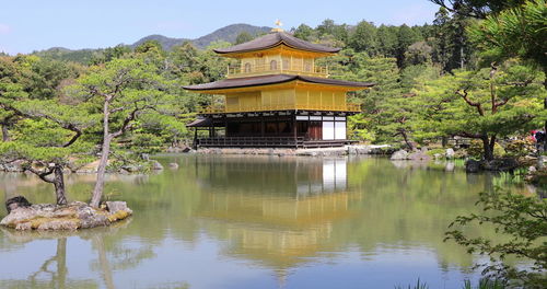 Built structure by lake and trees against sky