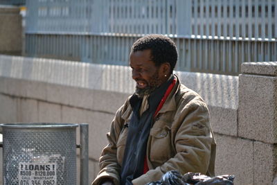 Man looking away while sitting in city