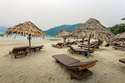 Deck chairs on beach against sky