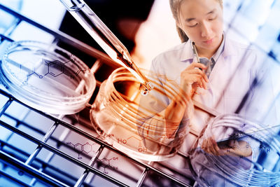 Double exposure of female doctor holding digital tablet and laboratory equipment