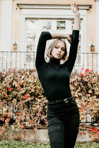 Portrait of smiling young woman standing against wall