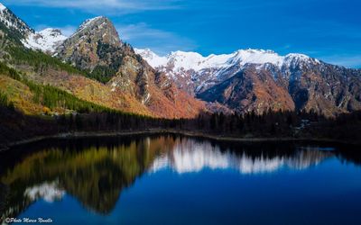 Scenic view of lake by mountains against blue sky