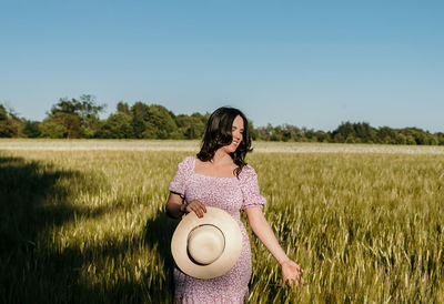 Beautiful woman touching wheat ears in field