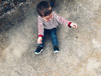 High angle view of boy crying while sitting on footpath