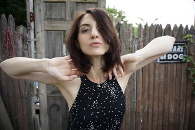 Portrait of beautiful young woman standing against wall