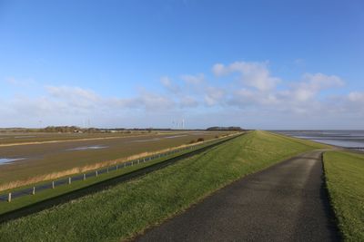 Road amidst field against sky